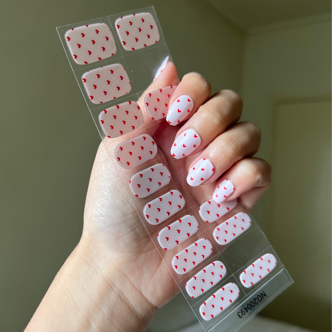 Hand holding a sheet of gellae nail art stickers with heart design