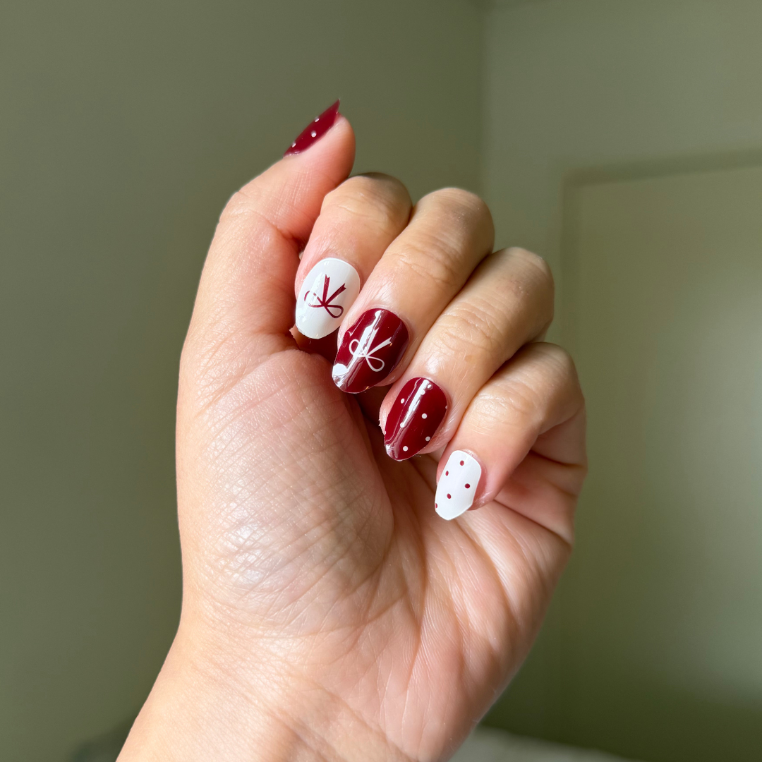 Hand with red and white gellae nail art on a neutral background